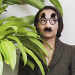 Businesswoman hiding behind plant wearing disguise