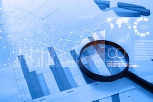 Magnifying glass and documents with analytics data lying on tabl